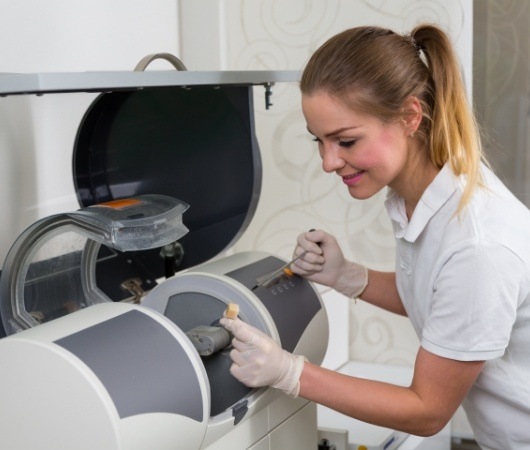 Dental team member taking same day dental crown out of milling machine