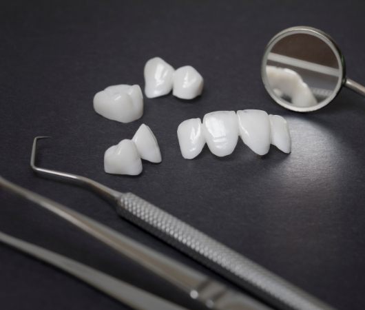 Several dental veneers on table next to dental instruments