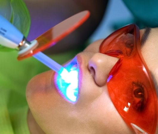 Woman getting her teeth professionally whitened by cosmetic dentist