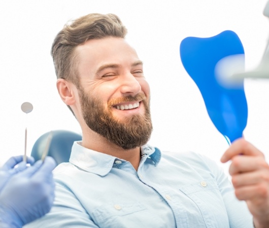 Man in dental chair seeing his smile in mirror