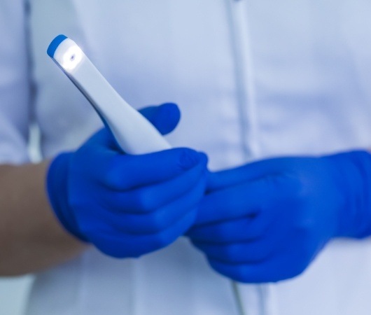 Dental team member holding thin white intraoral camera