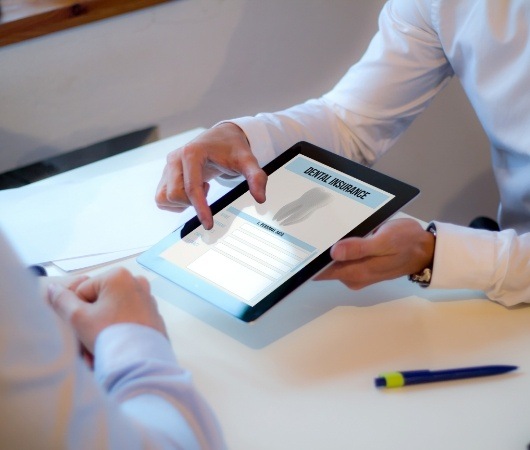 Two people looking at dental insurance forms on tablet