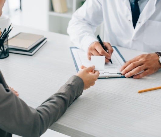 Patient handing a payment card to their dentist