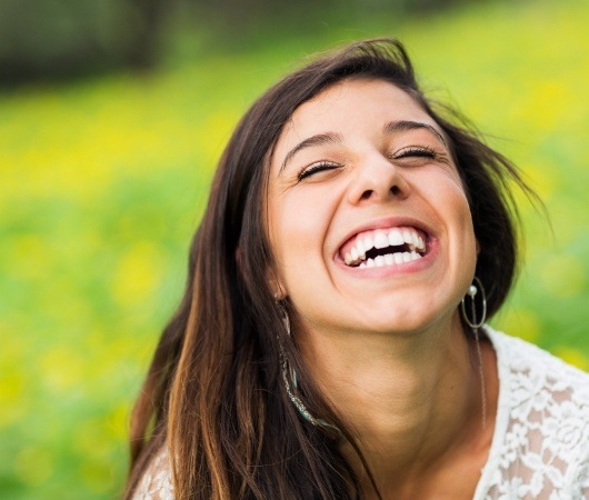 Young woman grinning while sitting in grass