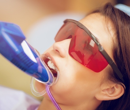 Young woman in dental chair with fluoride treatment tray over her teeth