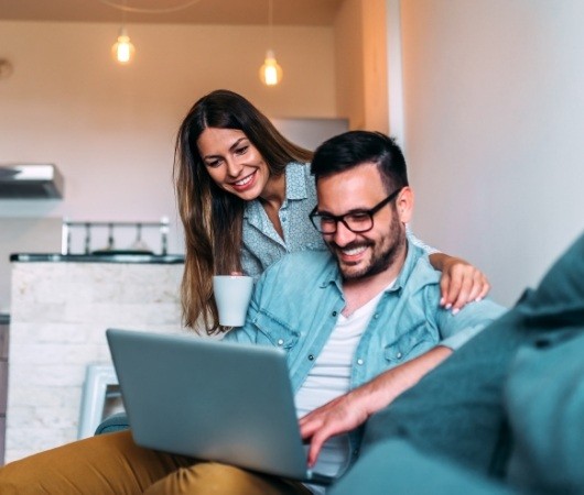 Man and woman looking at laptop for dentist reviews in Derry