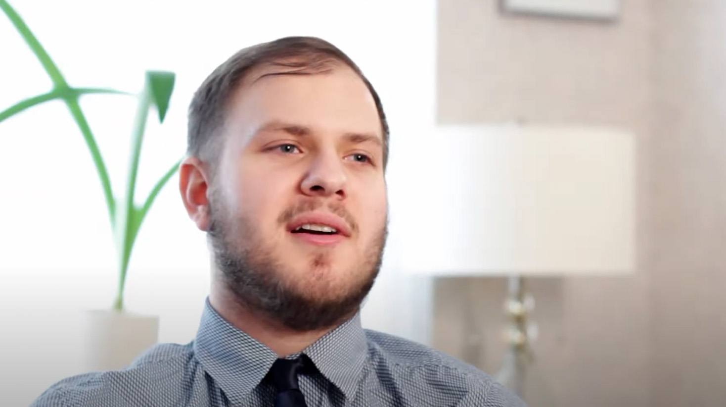 Man in black and white plaid collared shirt and tie