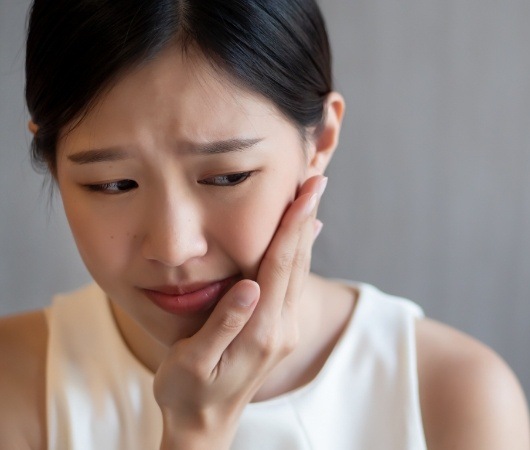 Woman holding her cheek in pain needing T M J treatment in Derry