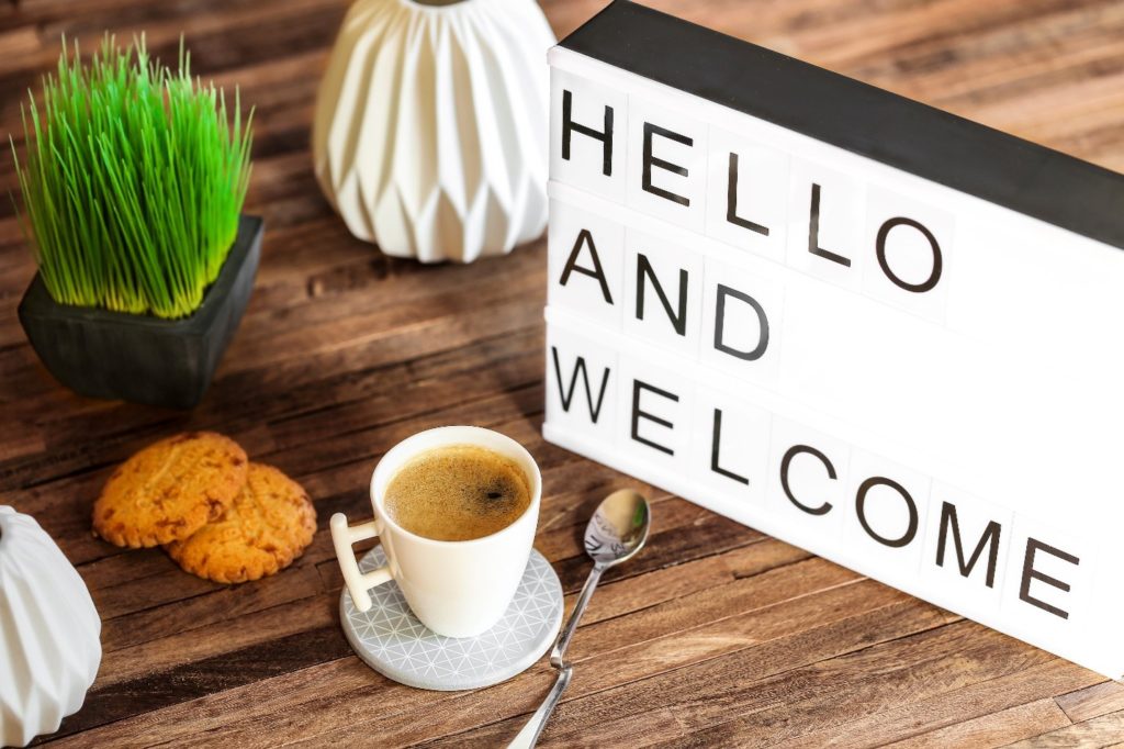 Hello and welcome sign on desk with coffee, cookies, and plants